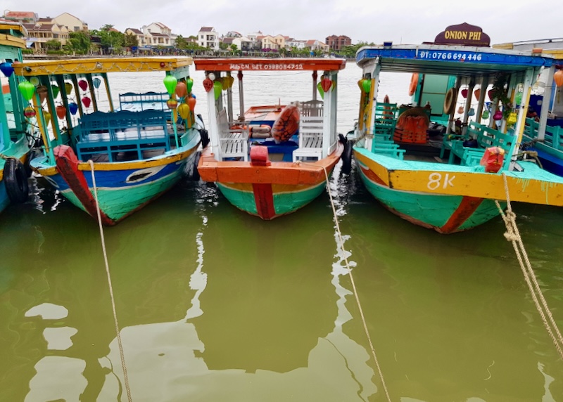 Colorful boats sit tied to the shore, waiting for passengers.