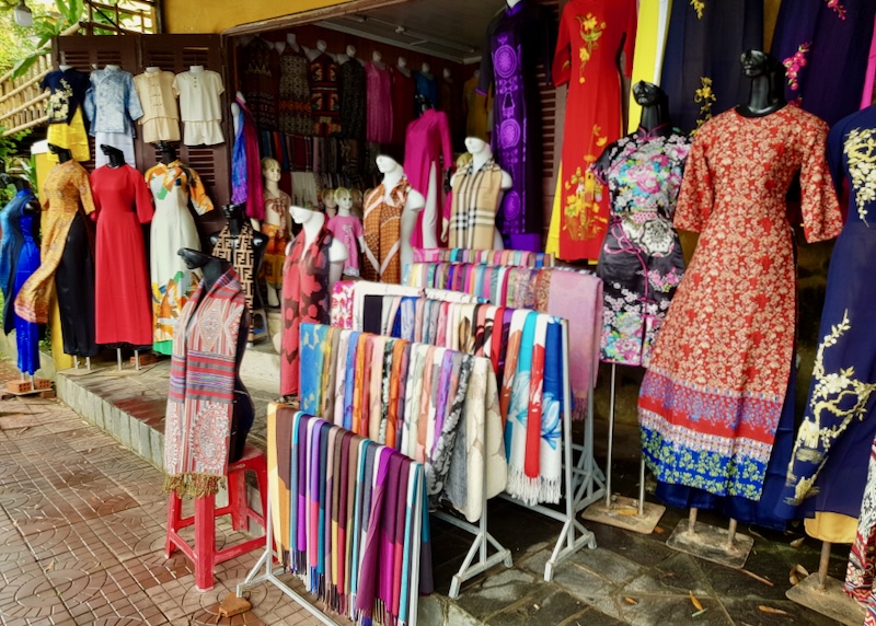 Colorful dresses and scarves fill a boutique.