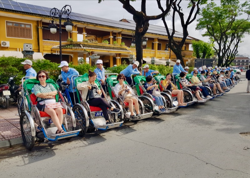 People sit and wait in the seat of cycle rickshaws.