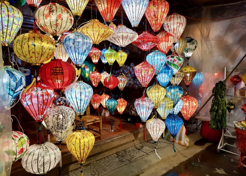 Colorful lanterns for sale hang on strings at a night market.