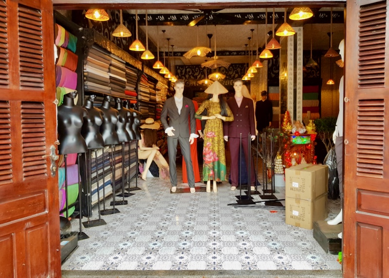 A fabric shop with mannequins dressed in tailored suits and dresses.