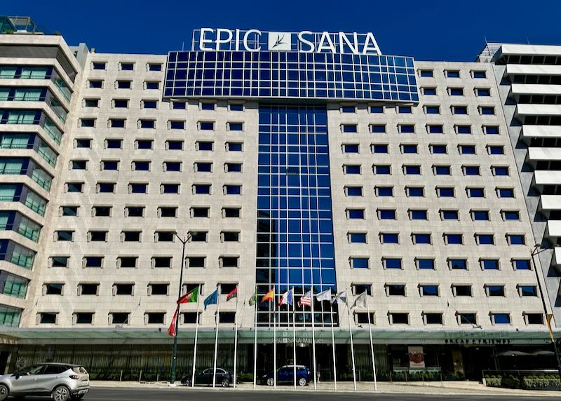 Large white hotel building with a line of flags flying in front