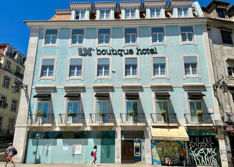 Exterior of a baby blue traditional-style hotel in Lisbon, with pedestrians passing in front