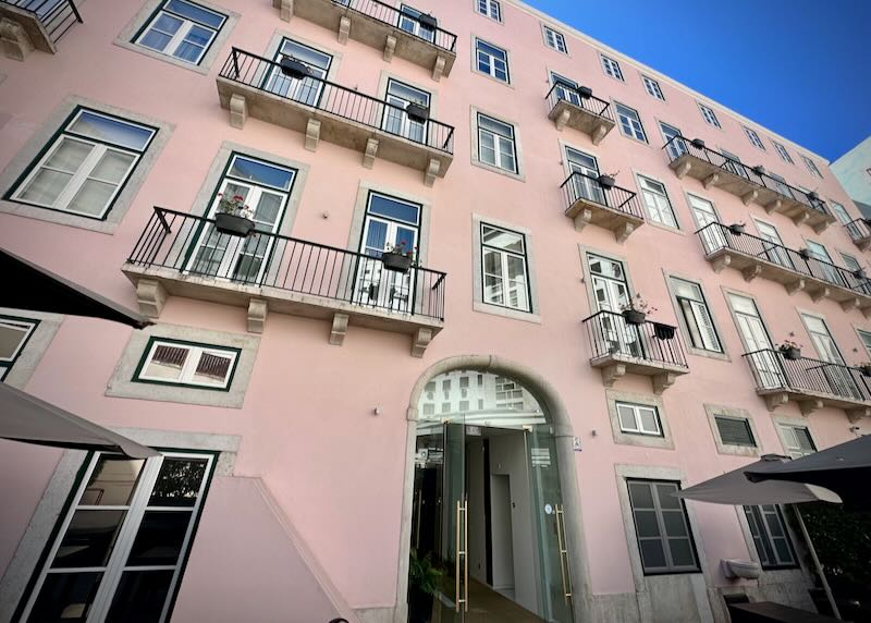 Pink exterior of a hotel in Lisbon, with juliet balconies at many of the windows