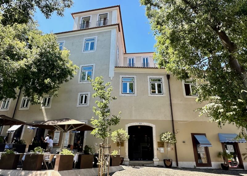 Exterior view of a tan stucco hotel building in Lisbon on a sunny day