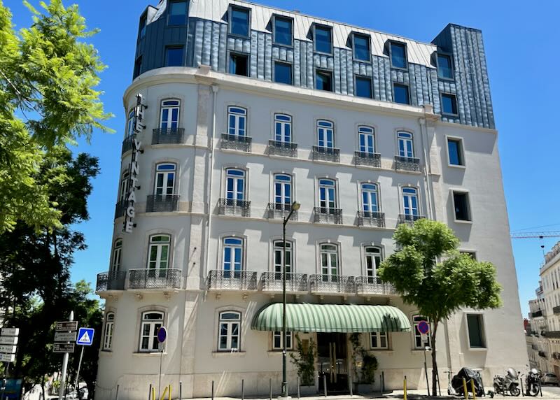 Exterior of an art-deco inspired hotel in Lisbon with a green striped awning over the entryway