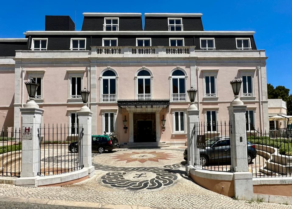 Gated entrance to a posh pink historic hotel building in Lisbon.