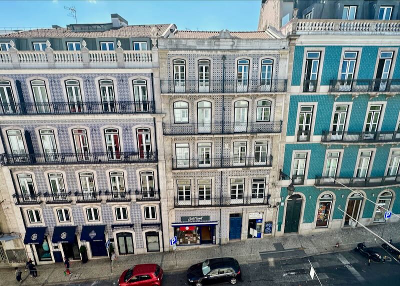 Colorful and ornately painted buildings with iron balconies, viewed from a high angle across the street