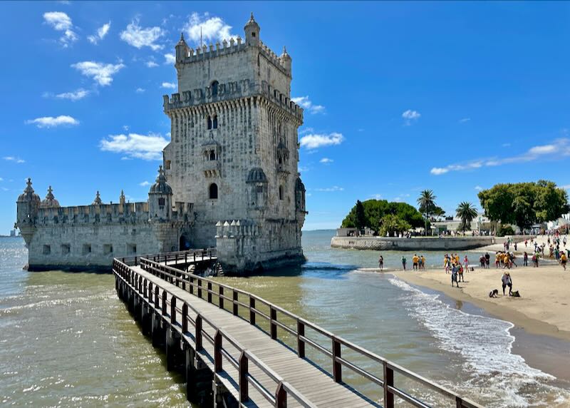 The Belem Tower in Lisbon, with people playing in the adjacent sand and surf