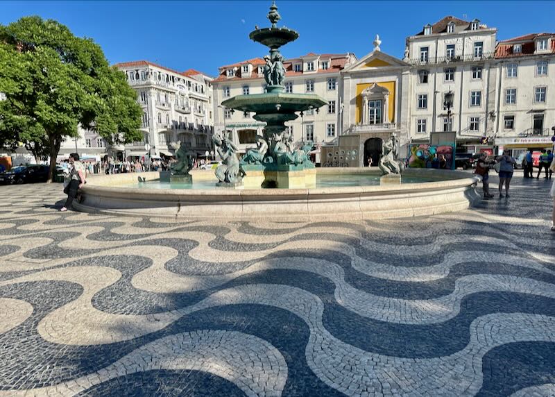 Plaza lined with colorful buildings and paved with black and white tiles in a wave pattern