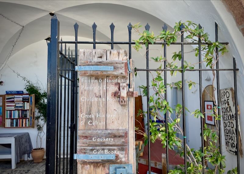 Rustic handpainted sign for a bookstore, hung on a wrought-iron gate.