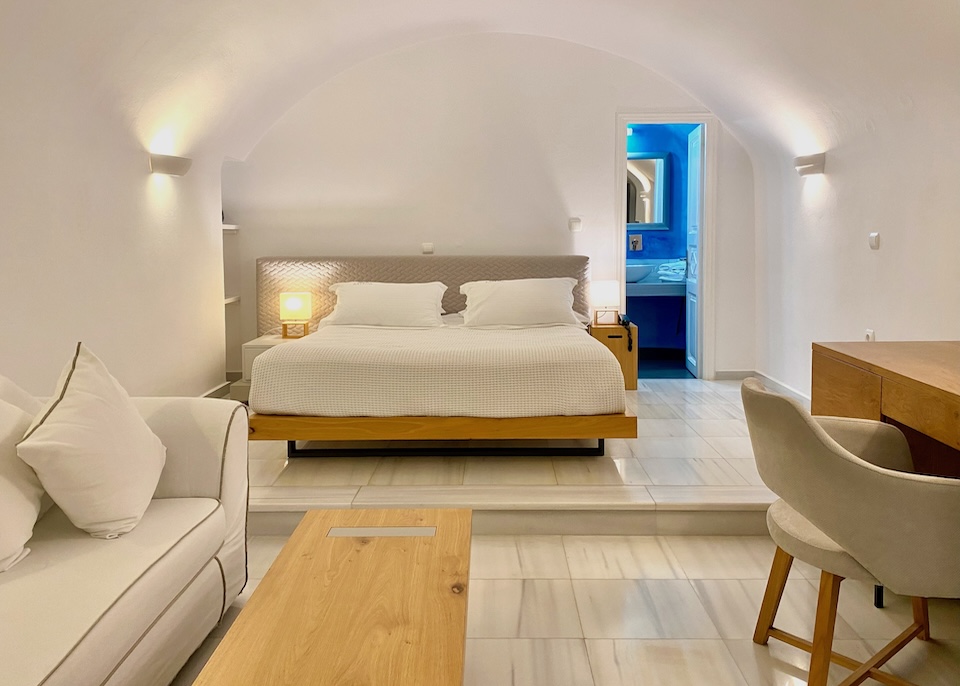 Whitewashed walls, barrel-vaulted ceiling, and marble floors with a blue bathroom in a hotel suite in Santorini