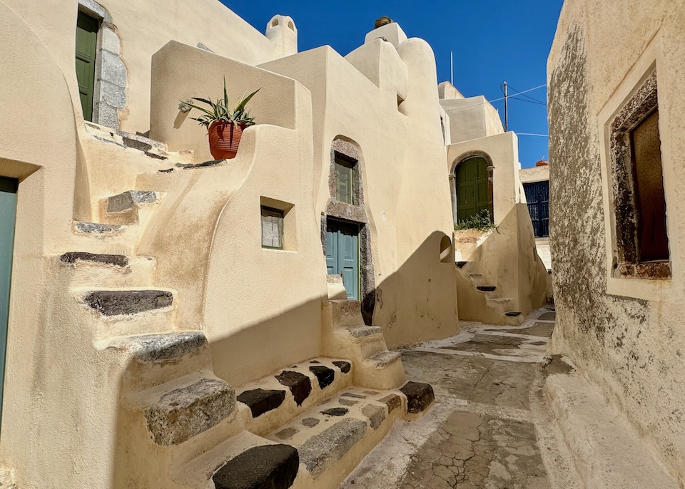 Distinctive, cave-style homes with exterior staircases on a narrow footpath in Santorini