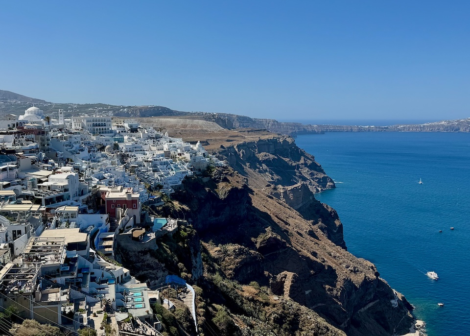 View of Fira village with the caldera, sea, and boats below in Santorini