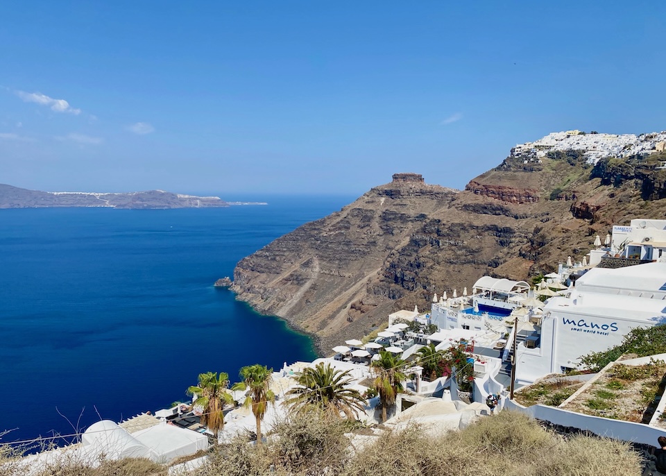 View of some hotels in Firostefani above the caldera with Skaros Rock and Imerovigli in the distance in Santorini