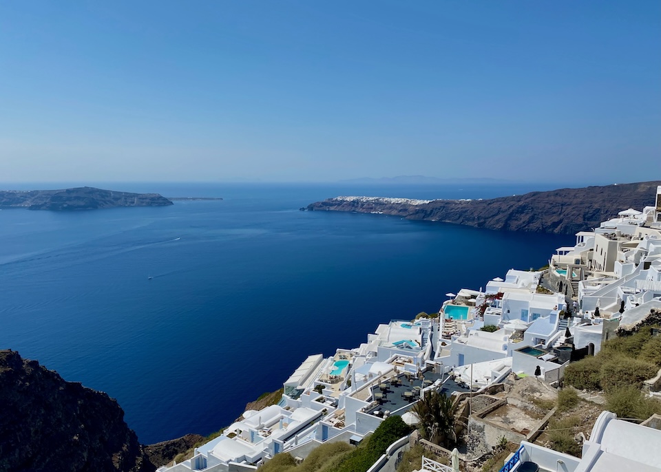 View of hotels and swimming pools over the caldera with Oia and Thirassia in the distance