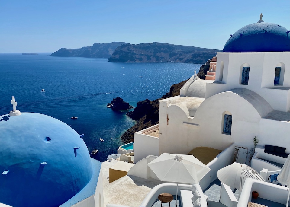 Two of Santorin's iconic blue domes on white church buildings overlooking the caldera and sea in Oia Santorini