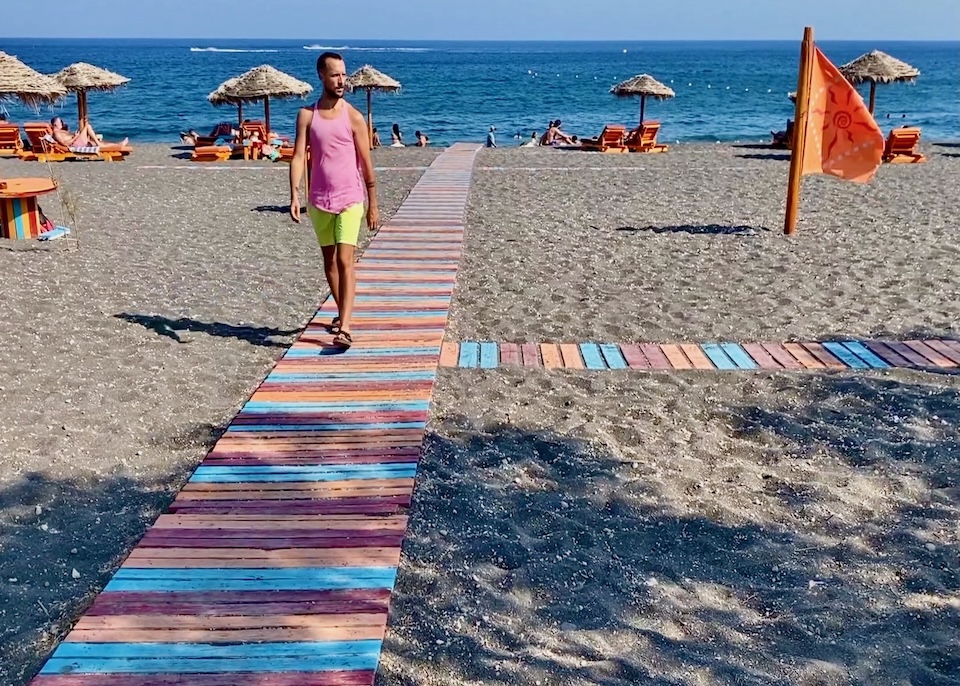 Colorful beach boardwalk leading from the sand to the sea with sunbeds and umbrellas