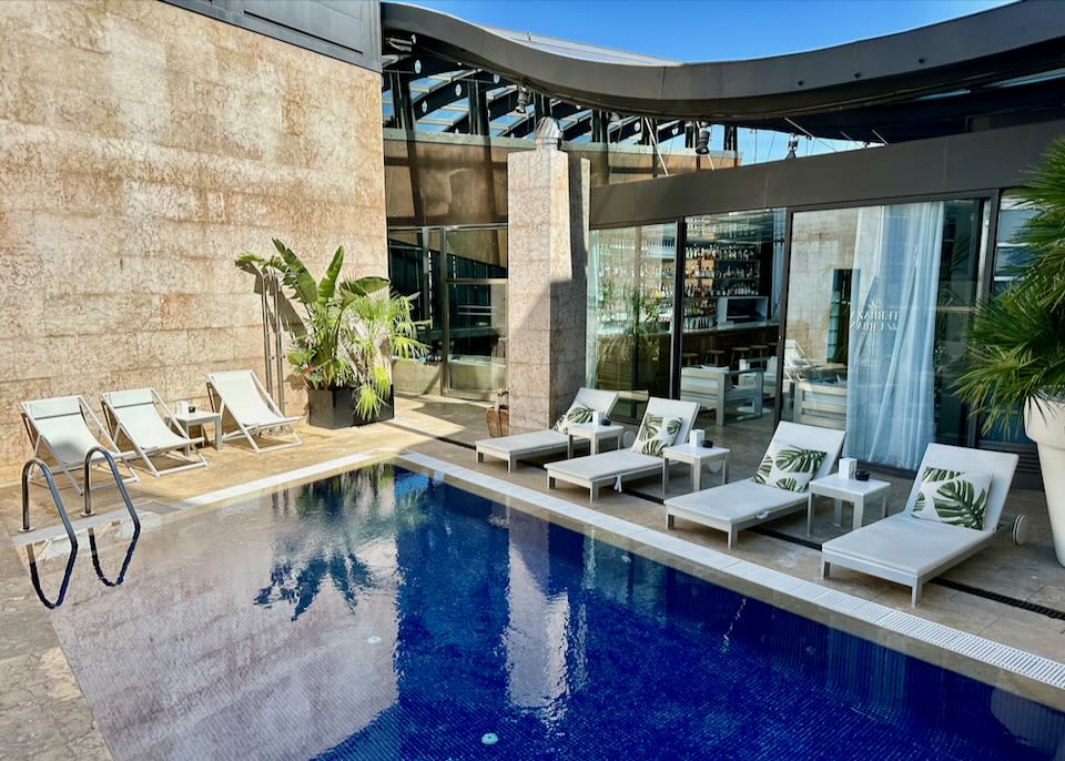 Rooftop hotel swimming pool, with sun loungers on a sunny day.