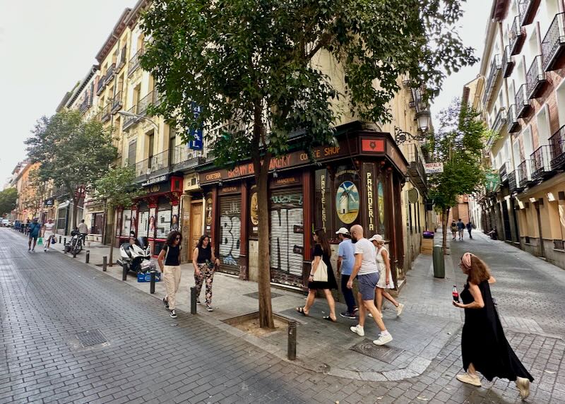 Pedestrians walk past a busy shop corner in Madrid's Huertas neighborhood.