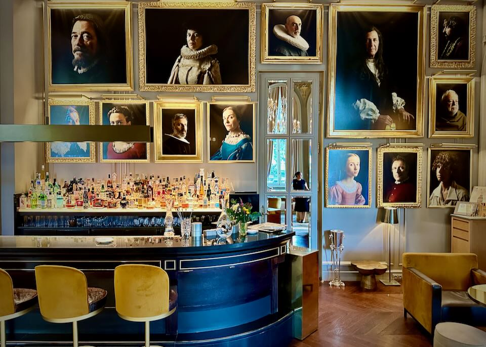 Bar with moody portrait paintings hung floor to ceiling.