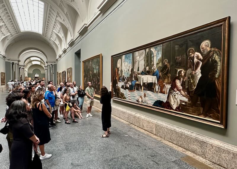 A tour guide instructs a group about a painting hanging in the Prado Museum