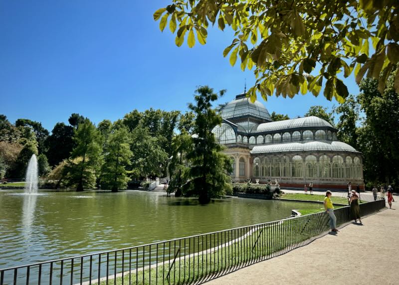 Glass conservatory building with a pond and fountain in front