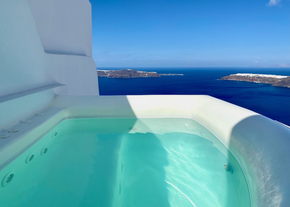 A semi-shaded outdoor jacuzzi facing the caldera, Thirassia, and Oia at Above Blue in Imerovigli, Santorini.