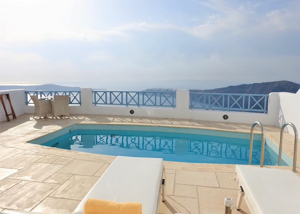 A private plunge pool on stone terrace with two sunbeds above the caldera at Absolute Bliss hotel in Imerovigli, Santorini.