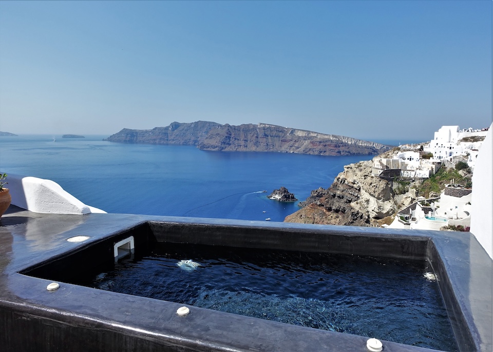 A black painted plunge pool with a caldera view toward Thirassia Island and Oia village at Alta Mare hotel in Oia, Santorini.