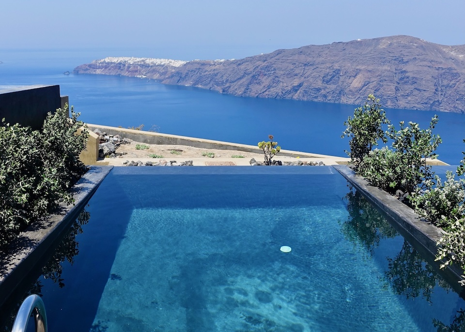 A coal black private, infinity plunge pool with a view over the caldera toward Oia village at Andronis Concept Wellness hotel in Imerovigli, Santorini.