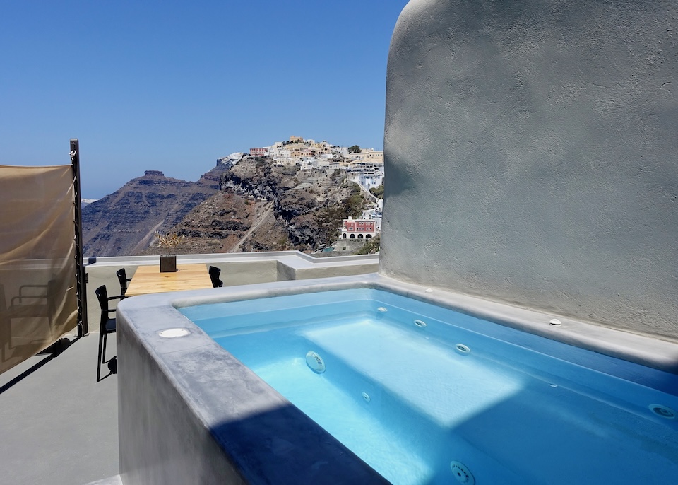 A private jacuzzi with a view toward Skaros Rock on a terrace separated from its neighbor by a screen at Aria Villas in Fira, Santorini.