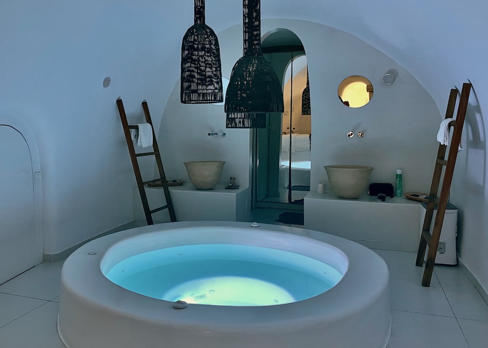 A round, indoor jacuzzi in a cave-style bathroom at Aroma Suites in Fira, Santorini.