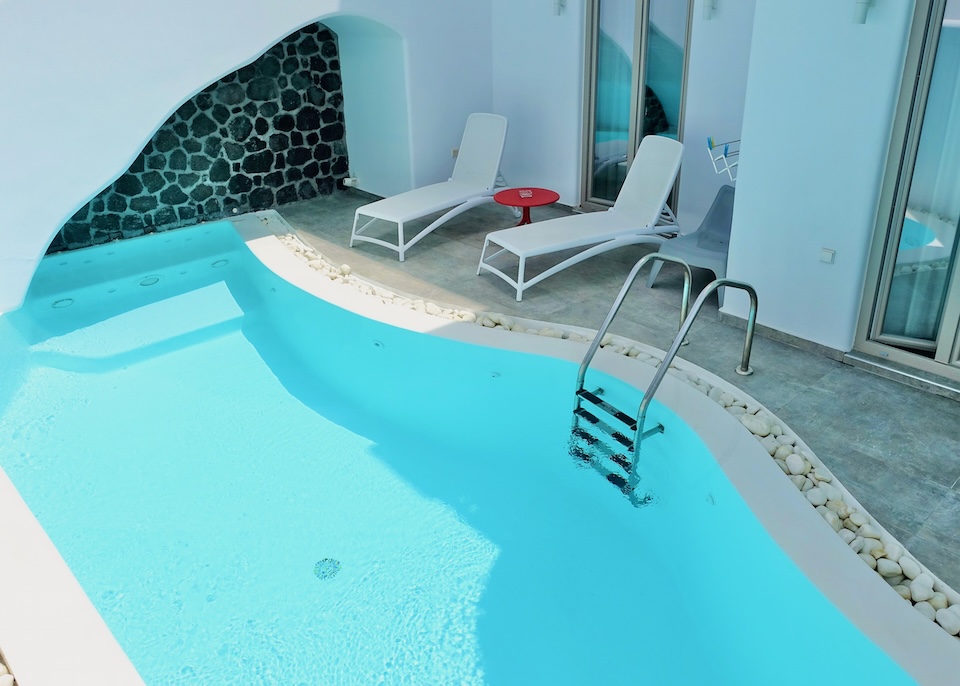 A freeform private pool with a pair of sunbeds in front of a suite at La Belezza Eco Boutique in Kamari, Santorini.