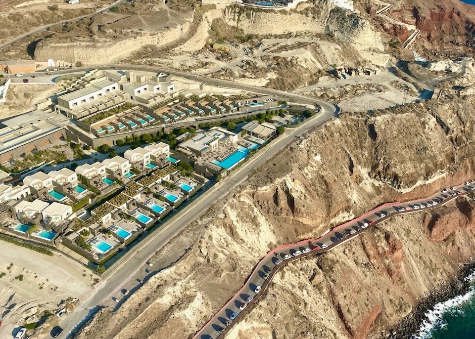 Aerial view of Canaves Epitope showing its main pool and private pools above the sea in Oia.