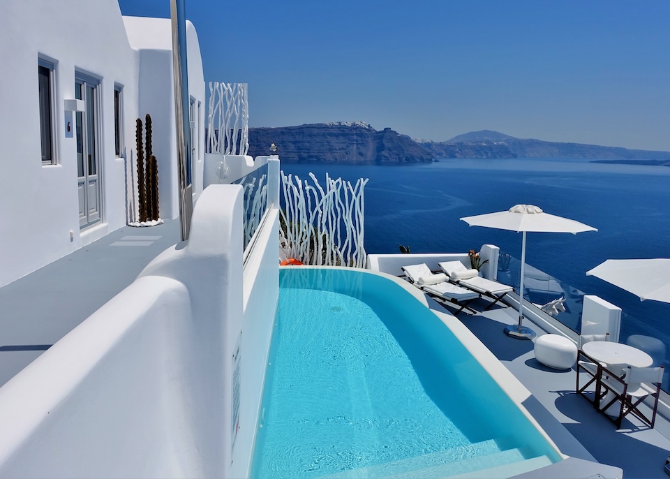 A curved edge pool in between an villa and its sun terrace overlooking the caldera at Canaves Sunday Suites in Oia, Santorini.