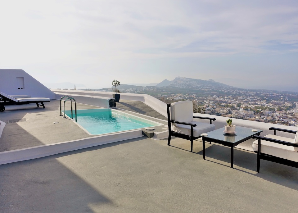 A private plunge pool on a large furnished terrace with panoramic views over the who island at Carpe Diem in Imerovigli, Santorini.