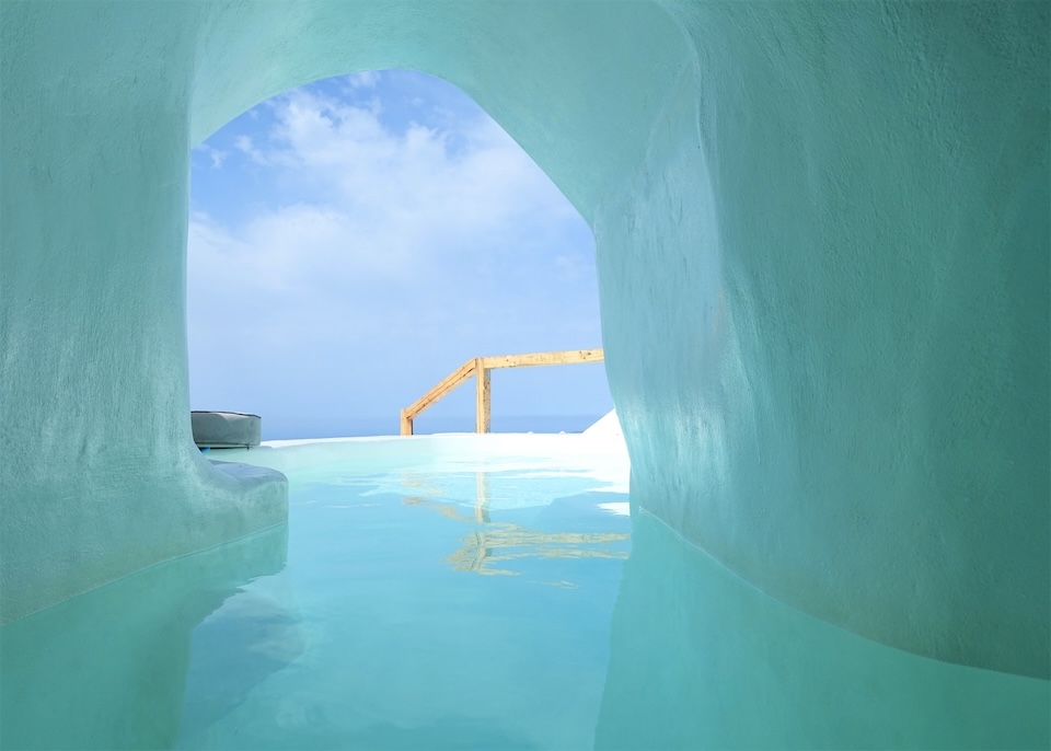 Inide a cave pool reflecting blue light on its walls facing the sea and sky that blend together at Cocoon