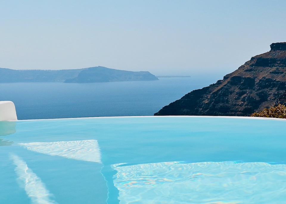 Closeup of an infinity pool above the caldera with a view to Skaros Rock and Thirassia Island at Dana Villas and Infinity Suites in Firostefani, Santorini.