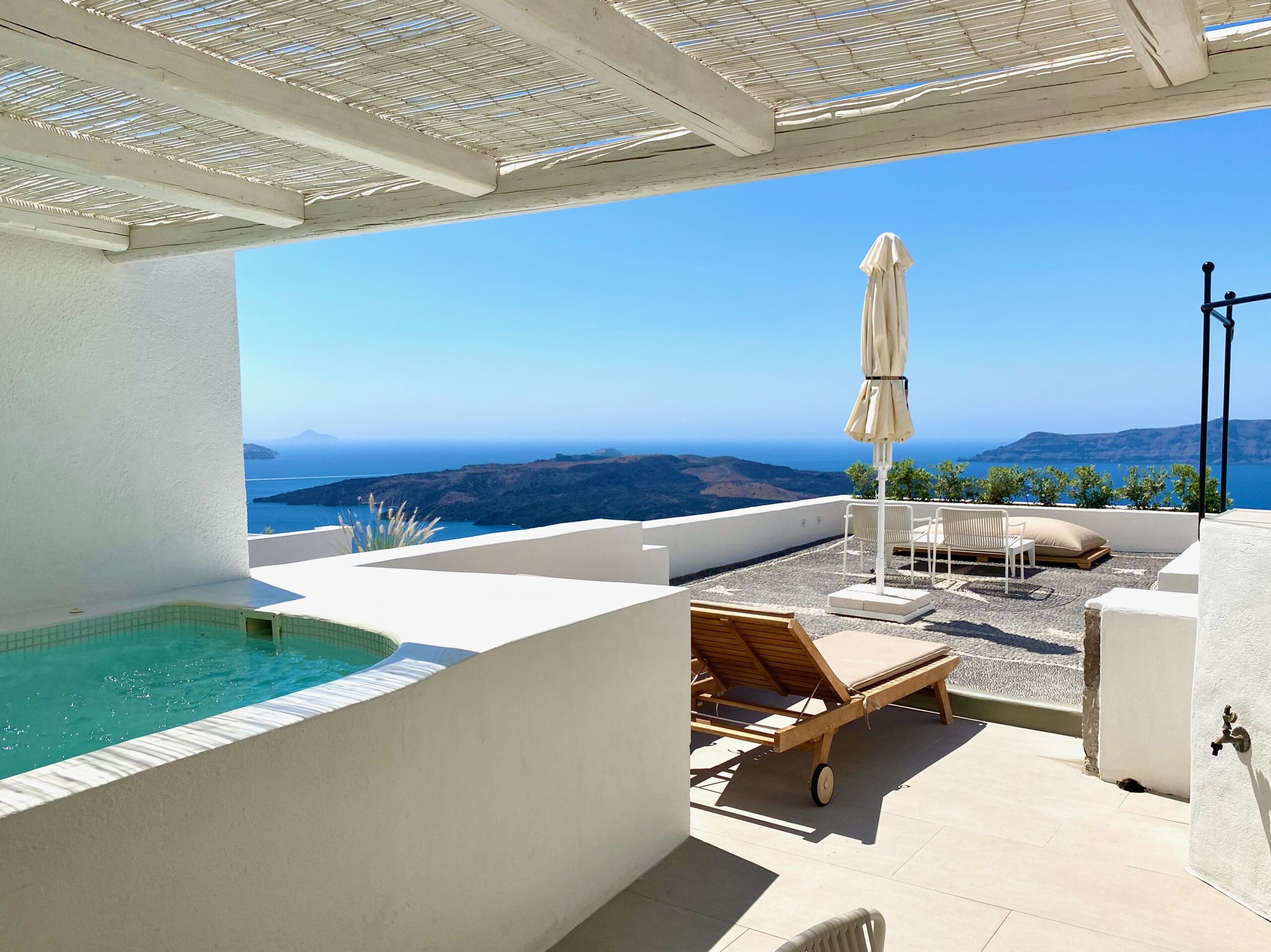 An outdoor jacuzzi under a pergola on a roomy private terrace with volcano views at Enigma Suites in Fira, Santorini.