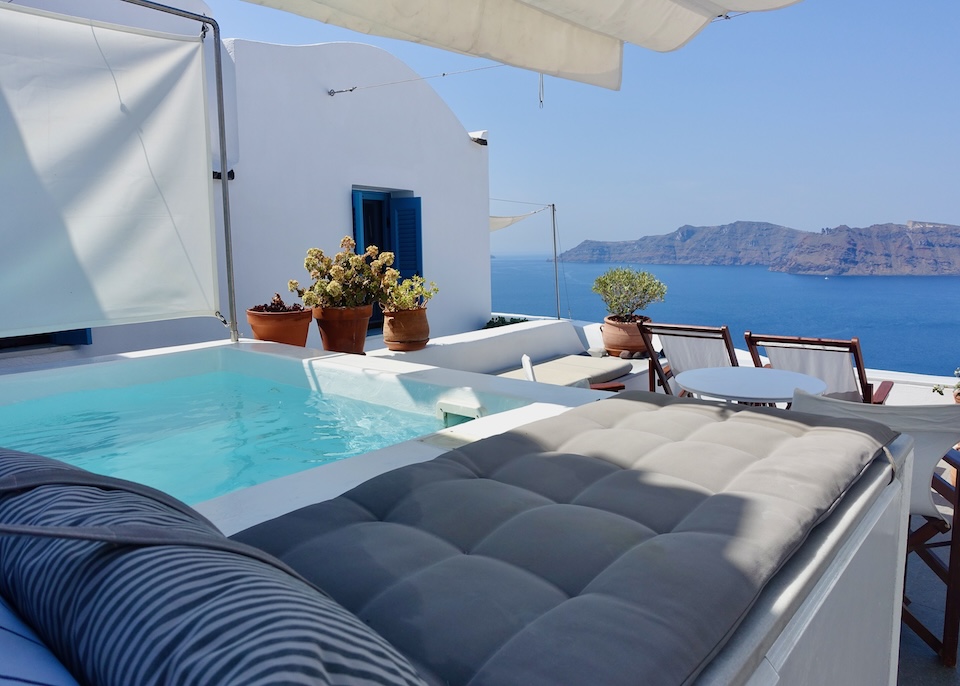 A private jacuzzi and sun lounger on a terrace above the caldera, separated from its neighbor by a sail cloth at Gabbiano Traditional Cave Houses in Oia, Santorini.