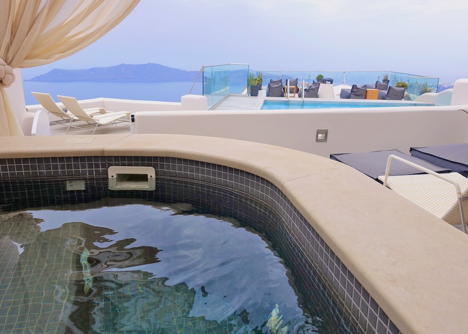 A private, outdoor jacuzzi on a canopied terrace behind the hotel's main pool at Galaxy Suites and Villas in Imerovigli, Santorini.