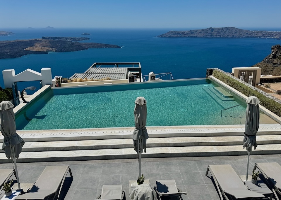 View from above the infinity pool overlooking the caldera with the volcanoes and Thirassia in the background at Aeifos Boutique Hotel in Imerovigli, Santorini.