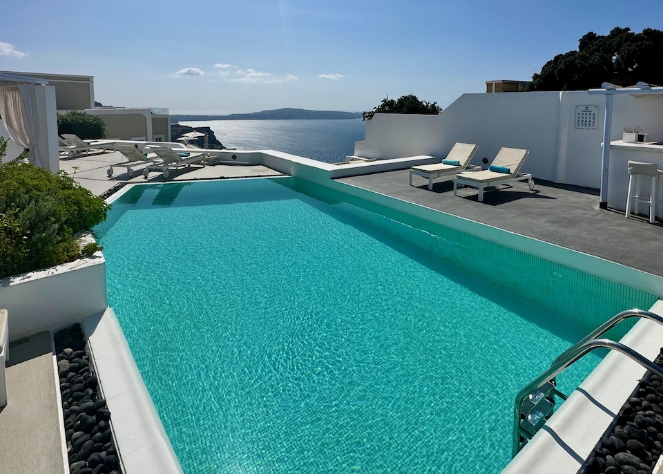 A large pool with a pair of sunbeds on each side and a view over the caldera at Aria Suites and Villas in Fira, Santorini.