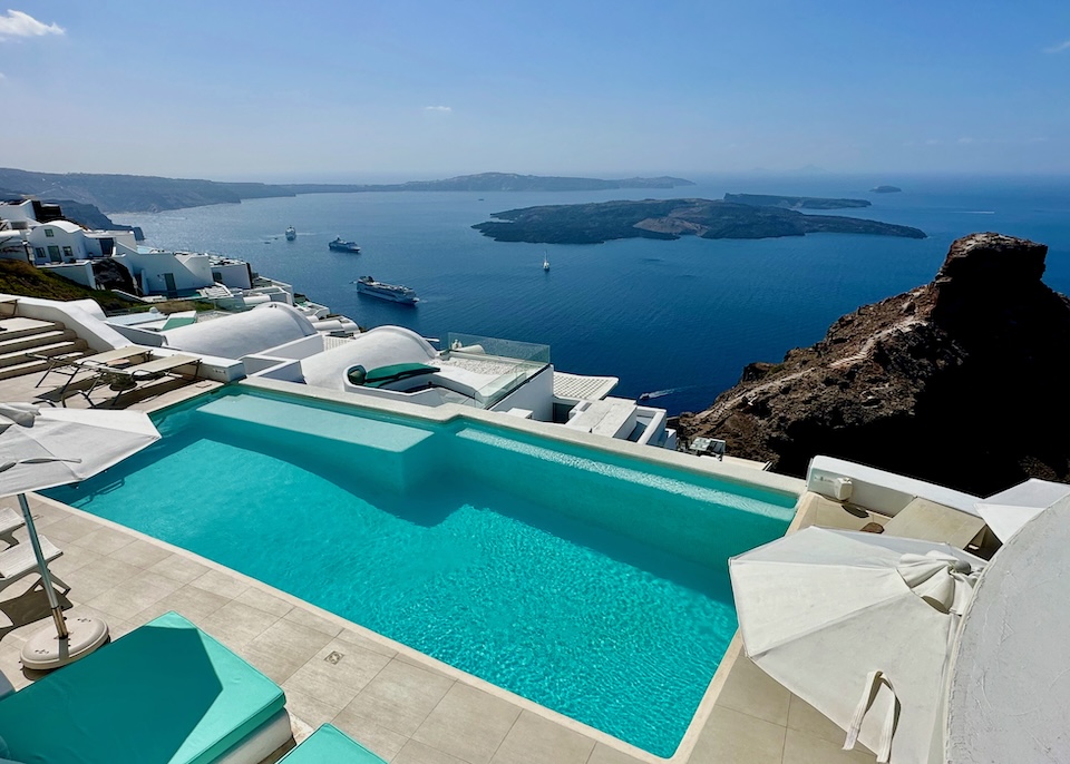 An infinity pool overlooking the caldera with Skaros Rock, the volcanoes, and ferry boats at Astra Suites in Imerovigli, Santorini