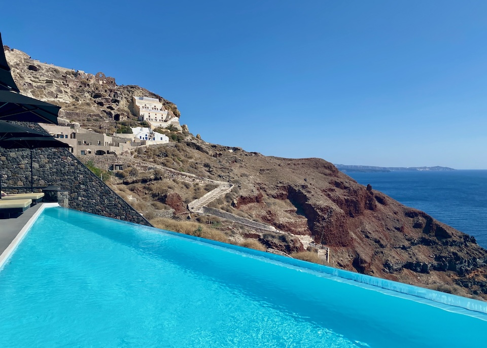 An infinity pool faces the caldera and a zigzagging path down the cliffside from the village above at Charisma Hotel in Oia, Santorini.