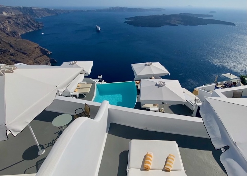 A private, furnished balcony overlooks an infinity pool, the caldera, and the volcanoes at Katikies Chromata hotel in Imerovigli, Santorini.