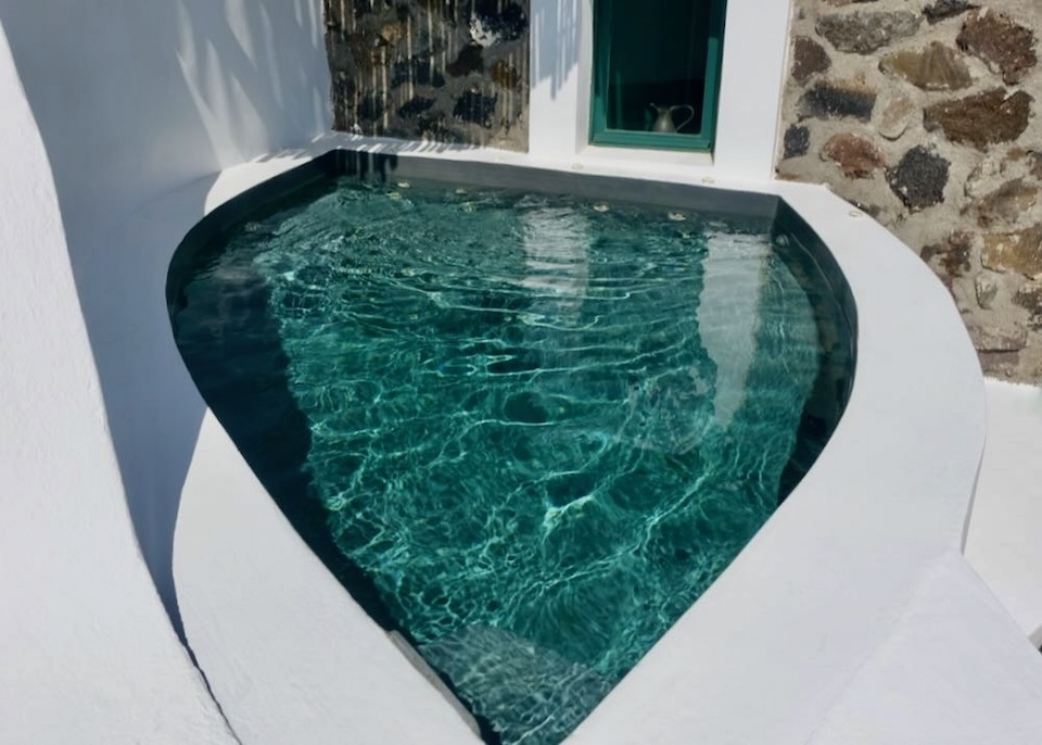 A teardrop-shaped plunge pool in front of a rock wall at The Vasilicos hotel in Imerovigli, Santorini.