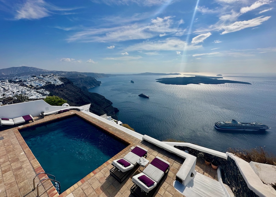 View from above a private pool on a terra cotta tiled terrace with views over the caldera and volcanoes at The Vasilicos hotel in Imerovigli, Santorini.