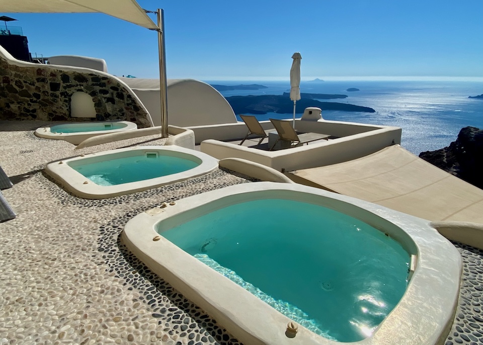 Three jacuzzis on a pebbled terrace overlook the caldera and volcanoes at Kapari Natural Resort in Imerovigli, Santorini.